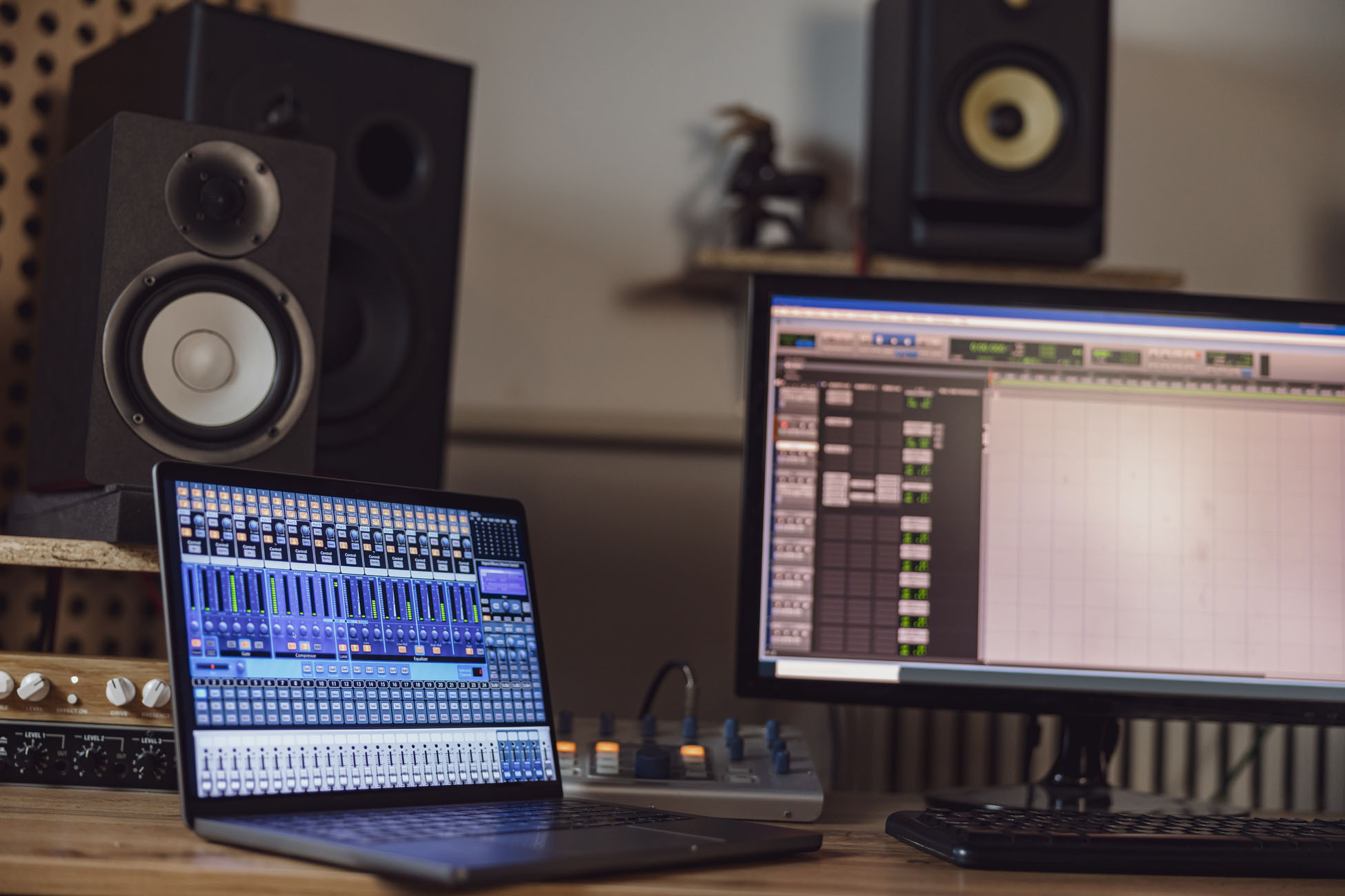 Close-up of switched on laptop and monitor screen on table in the sound engineer room in a broadcasting and recording studio